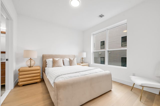 bedroom with light wood finished floors, visible vents, and baseboards