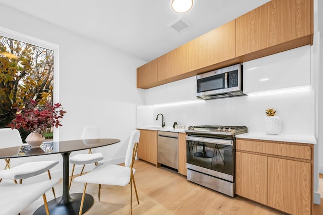 kitchen featuring visible vents, a sink, stainless steel appliances, light countertops, and light wood-type flooring