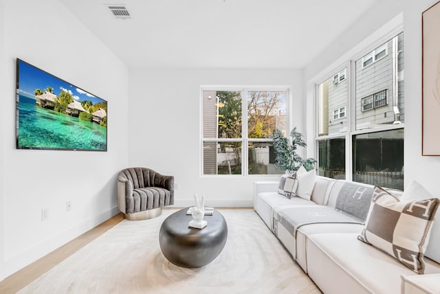 living area with visible vents, baseboards, and wood finished floors