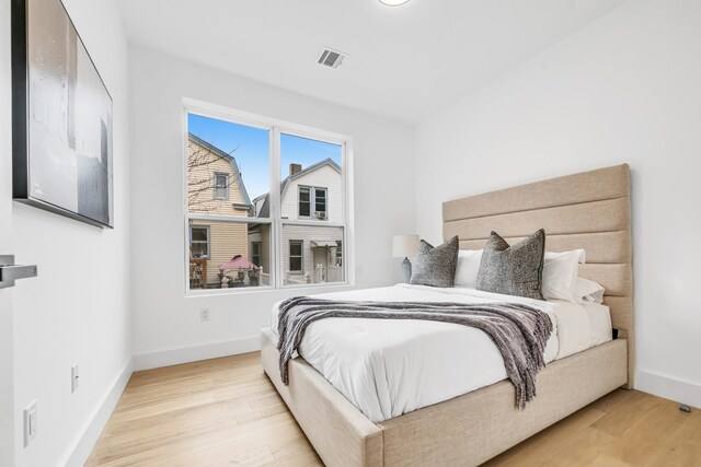 bedroom with visible vents, baseboards, and wood finished floors