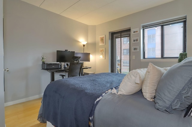 bedroom with light wood-style flooring, access to exterior, and baseboards