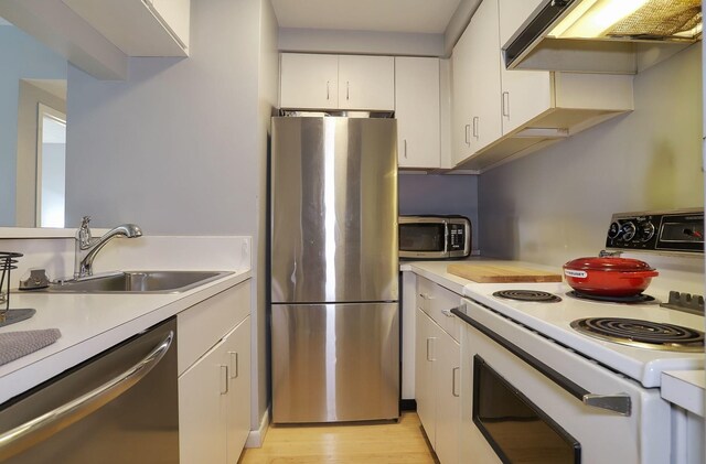 463 1st St Unit 3B, Hoboken, NJ 07030 - kitchen with appliances with stainless steel finishes, a sink, under cabinet range hood, light countertops, and white cabinetry
