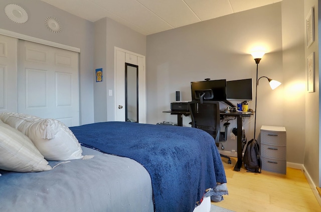 bedroom with light wood-style flooring, baseboards, and an office area