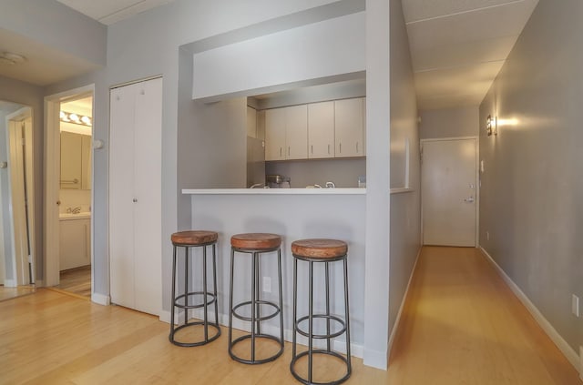 463 1st St Unit 3B, Hoboken, NJ 07030 - kitchen with light wood-style flooring, a kitchen breakfast bar, white cabinets, and baseboards