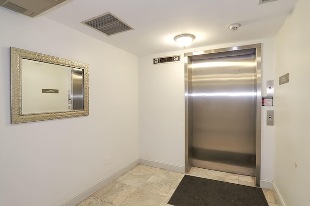 hallway with elevator and baseboards