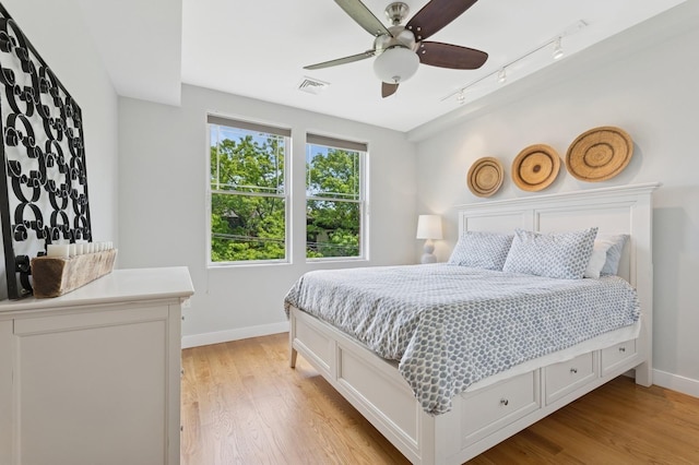 bedroom with baseboards, track lighting, light wood-style floors, and ceiling fan