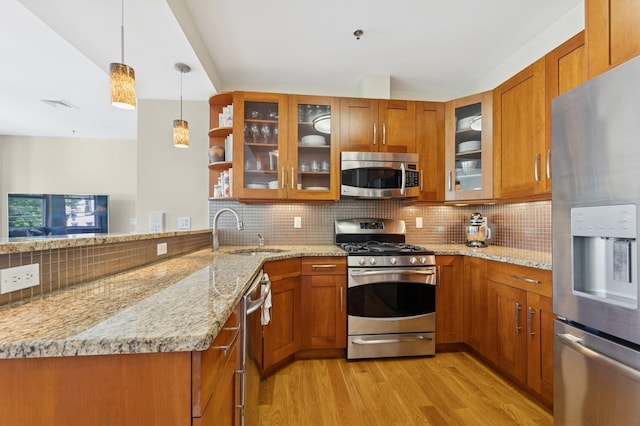 kitchen featuring stainless steel appliances, a sink, brown cabinets, light wood-style floors, and decorative backsplash