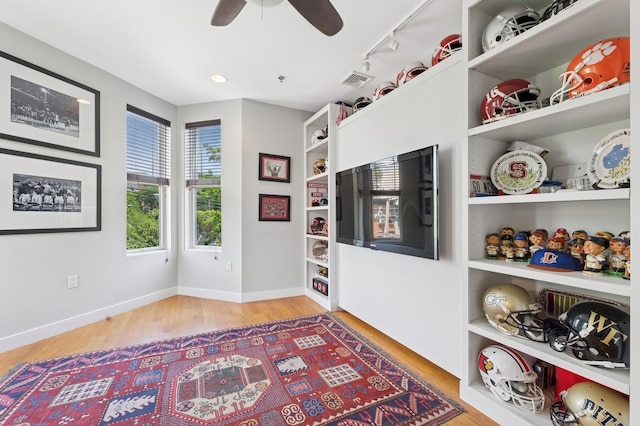 living area with wood finished floors, ceiling fan, track lighting, and baseboards