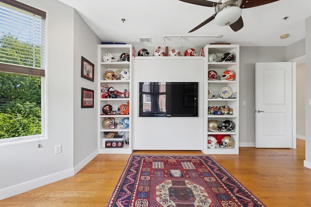 living room with healthy amount of natural light, ceiling fan, and light wood-style flooring