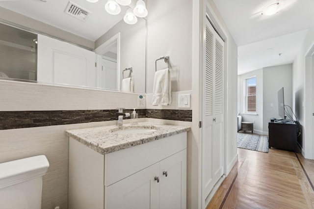 bathroom with toilet, wood finished floors, vanity, and a closet