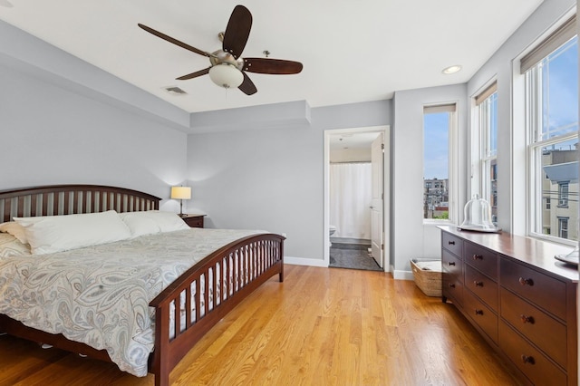 bedroom with baseboards, light wood-type flooring, a ceiling fan, recessed lighting, and ensuite bath