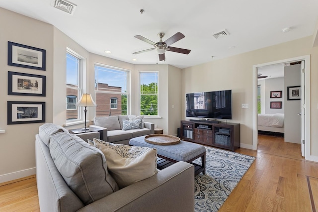 living room with light wood-type flooring, baseboards, and ceiling fan