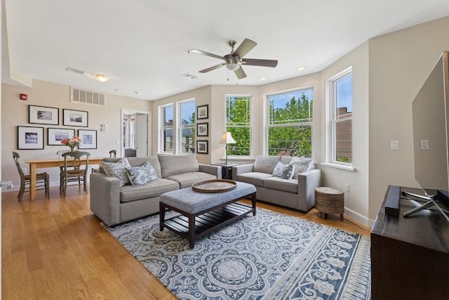 living room featuring light wood-type flooring, ceiling fan, and baseboards