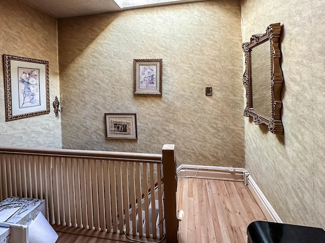 hallway with wood finished floors and an upstairs landing