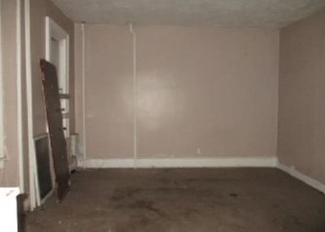 unfurnished room featuring baseboards and radiator heating unit