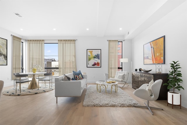 living room with beam ceiling and light wood-type flooring