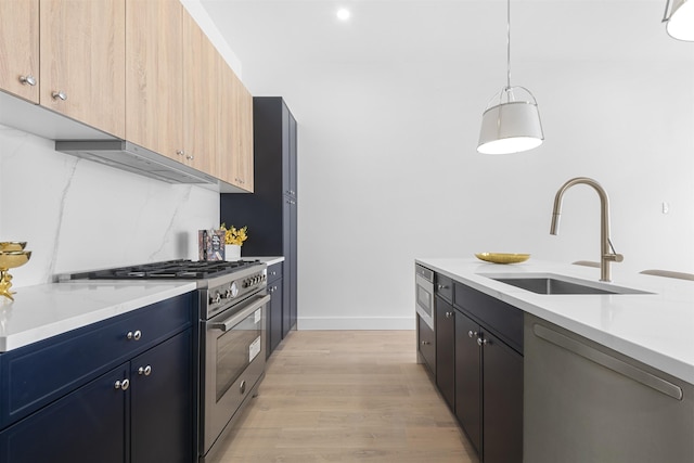 kitchen with light brown cabinetry, stainless steel range, dishwashing machine, sink, and pendant lighting