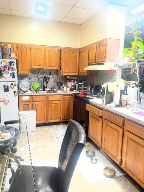 kitchen featuring sink, a drop ceiling, light tile patterned floors, backsplash, and white fridge