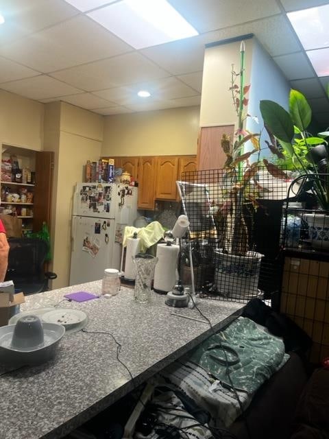 kitchen featuring a drop ceiling, decorative backsplash, and white fridge