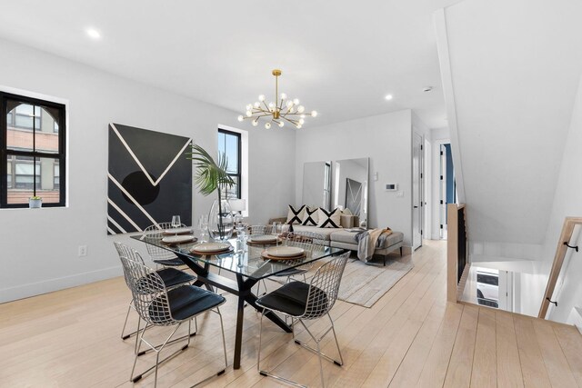 kitchen with sink, hanging light fixtures, a kitchen island with sink, stainless steel appliances, and light wood-type flooring