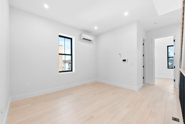 empty room featuring a wall mounted air conditioner and light hardwood / wood-style floors