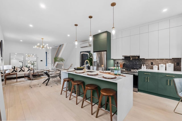 kitchen with light wood finished floors, green cabinetry, decorative backsplash, appliances with stainless steel finishes, and a sink