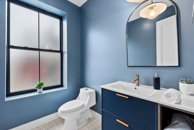 half bathroom with tile patterned floors, toilet, vanity, and baseboards