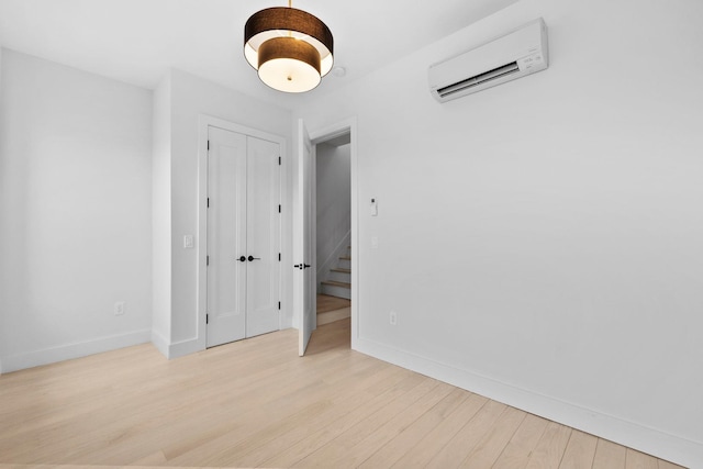 spare room with wood finished floors, baseboards, and a wall mounted air conditioner