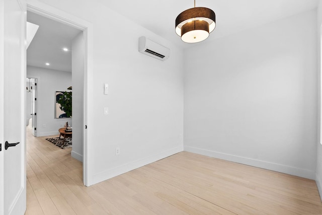 empty room with recessed lighting, baseboards, a wall mounted AC, and light wood-style floors