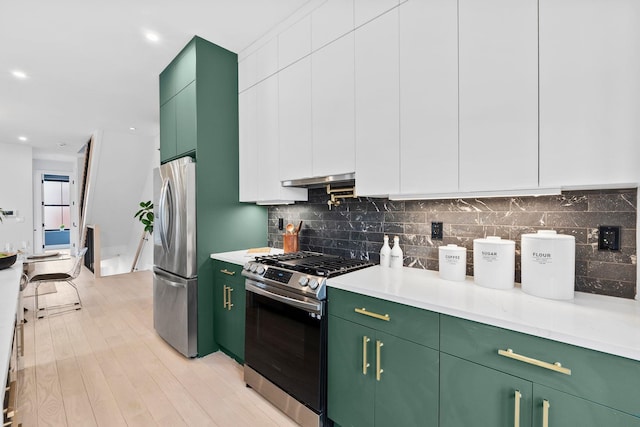 kitchen featuring light wood-style flooring, backsplash, stainless steel appliances, green cabinets, and light countertops