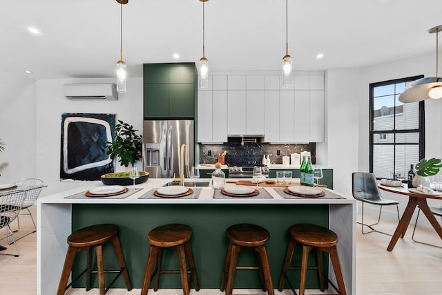 kitchen featuring backsplash, white cabinetry, a wall unit AC, a kitchen breakfast bar, and stainless steel appliances