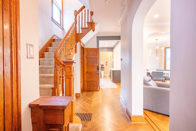 interior space featuring crown molding, a notable chandelier, and light parquet floors