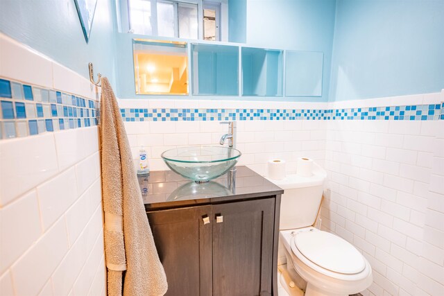 bathroom with vanity, toilet, and tile walls