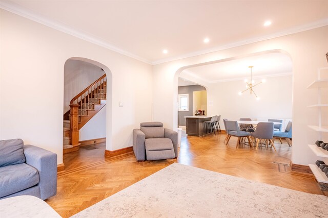 living room with light parquet floors, a chandelier, and crown molding