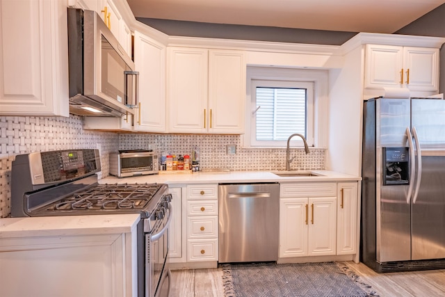 kitchen with white cabinets, light hardwood / wood-style floors, stainless steel appliances, and sink