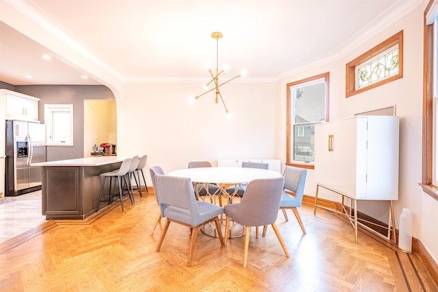 dining space featuring light parquet flooring, a notable chandelier, and ornamental molding