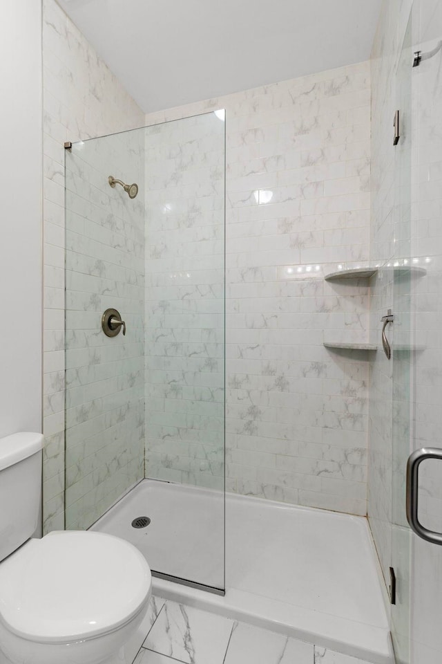 bathroom featuring a shower with shower door and toilet