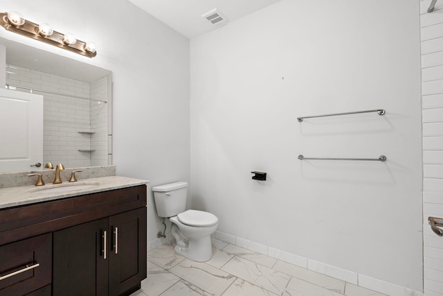 bathroom featuring vanity, toilet, and a tile shower