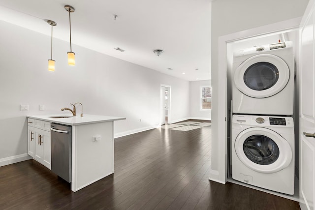 laundry room with dark hardwood / wood-style flooring, sink, and stacked washer and clothes dryer