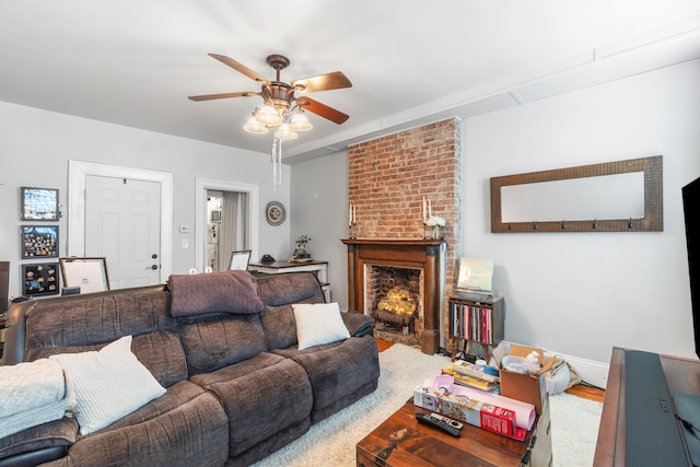 living area featuring ceiling fan, baseboards, and a fireplace