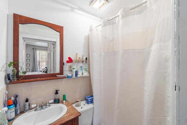 bathroom with vanity, toilet, tile walls, curtained shower, and tasteful backsplash