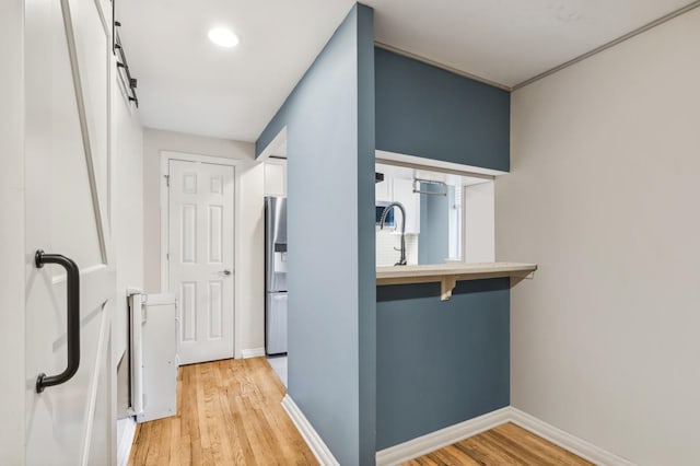 corridor featuring light wood-type flooring and sink