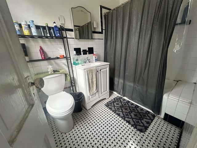 full bathroom featuring toilet, tile walls, backsplash, shower / bath combo, and vanity