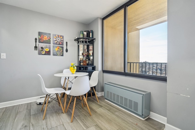 dining area featuring radiator, baseboards, and wood finished floors