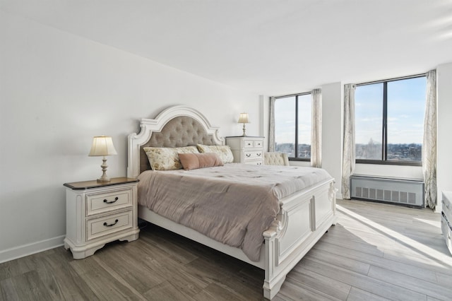 bedroom featuring radiator heating unit, baseboards, and wood finished floors