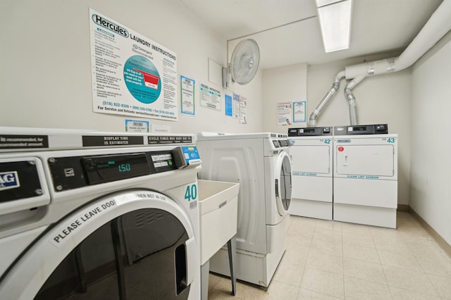 common laundry area featuring light tile patterned floors, washing machine and clothes dryer, and baseboards