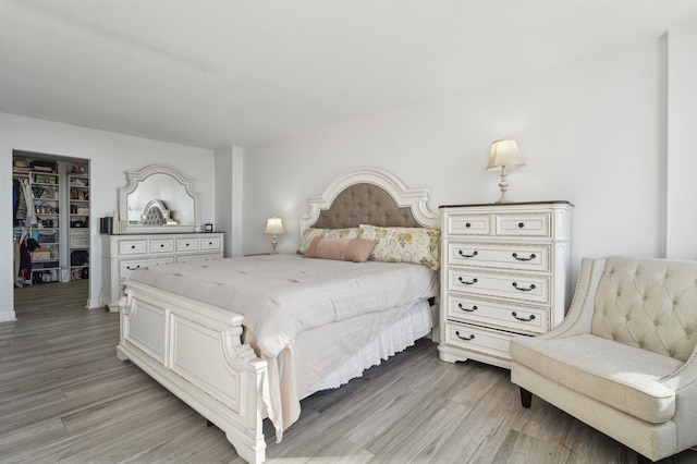 bedroom featuring light wood finished floors, a walk in closet, and a closet