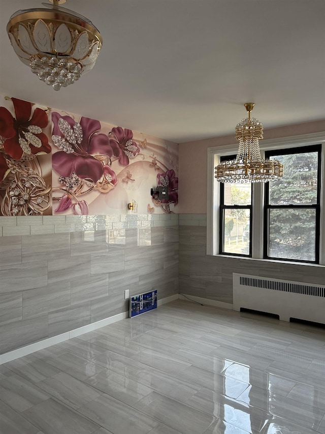 unfurnished dining area featuring a chandelier, radiator, and tile walls