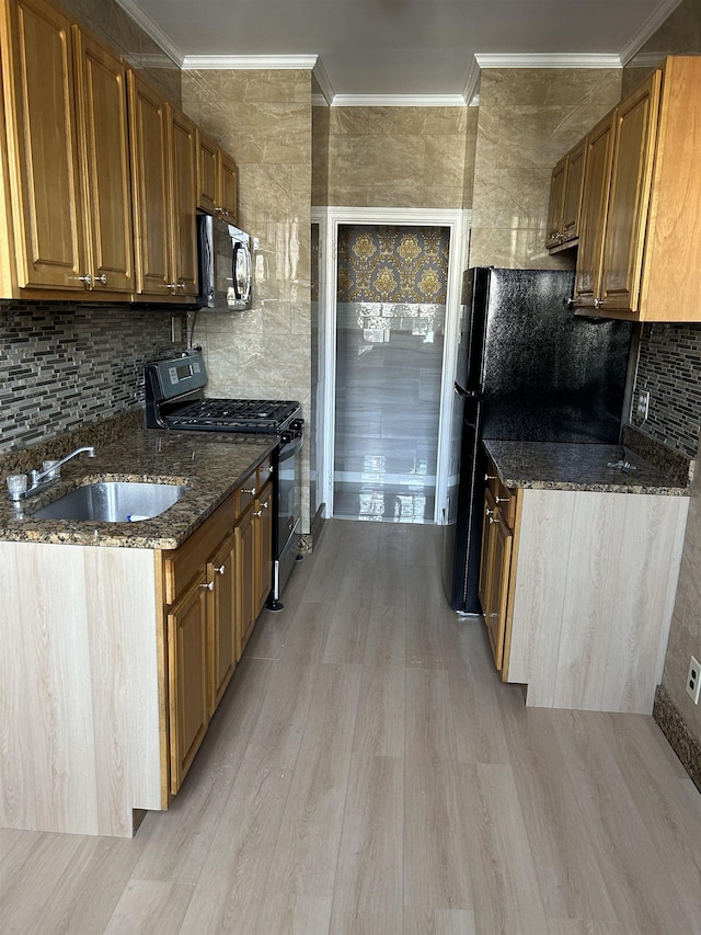 kitchen featuring ornamental molding, a sink, black appliances, light wood-type flooring, and backsplash