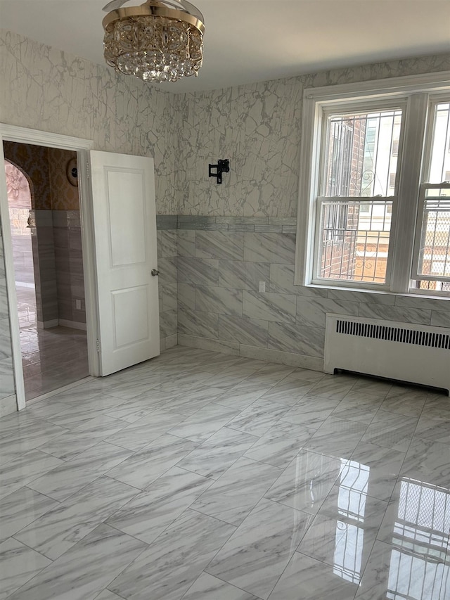 empty room featuring a notable chandelier, radiator, and arched walkways